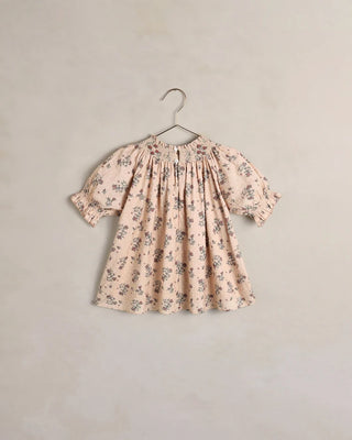 Back side of blush floral smocked dress with puff sleeves on hanger, flat product shot