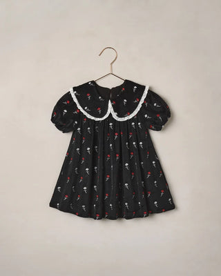 Noralee Janette Dress in black with red and white Winter Ditsy floral embroidery and a lace-trimmed collar, on a hanger