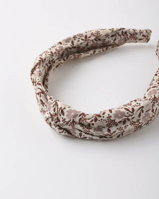 Close-up of a knotted headband in a taupe and brown floral print, shown at an angle against a white background.
