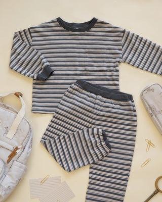 Striped midnight navy, cream, and rust sweatshirt and jogger set laid flat on a cream surface, styled with a kids' backpack, pencil case, notecards, and paperclips.