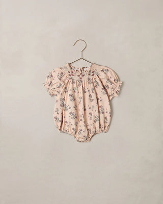 Blush floral smocked romper with embroidered neckline and puff sleeves on hanger, flat product shot