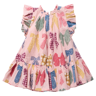 Product flat lay of a pink dress covered in a colorful printed bow pattern in gingham and stripe designs, featuring ruffle cap sleeves, a tiered ruffle skirt, and a back zipper closure, on a white background.