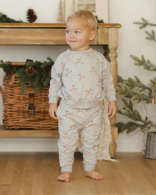 Child wearing a light gray pajama set with animal prints in a cozy room.