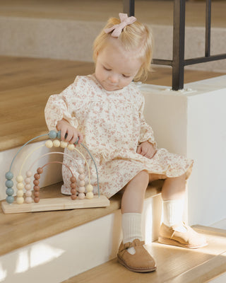 Child playing with a wooden bead toy on a wooden staircase