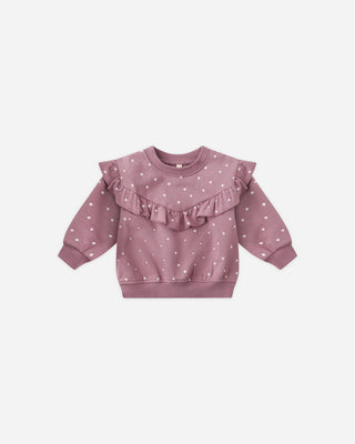 Pink baby sweater with ruffled details on a light pink background