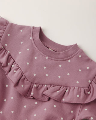 Pink polka dot dress with ruffled collar on a light background