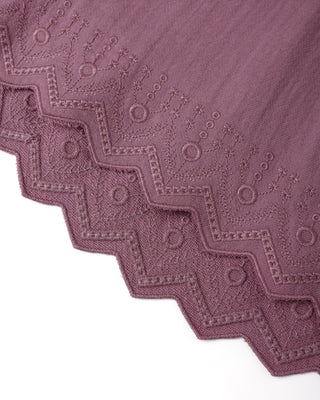 Close-up of a textured purple fabric with geometric patterns on a white background