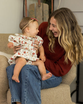 Woman sitting on a couch holding a baby, both smiling