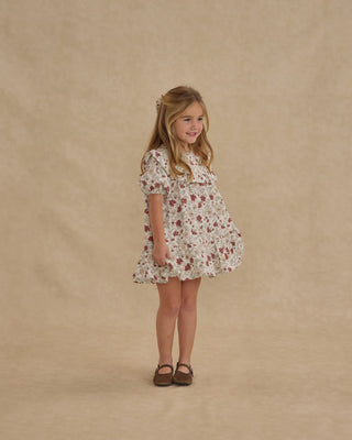Young girl wearing a floral dress against a beige background