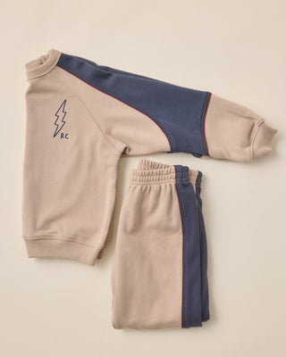 Folded beige and navy tracksuit on a light beige background