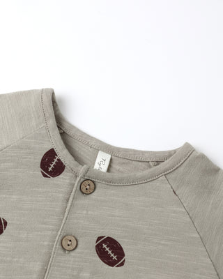 Gray baby romper with football designs and buttons on a white background