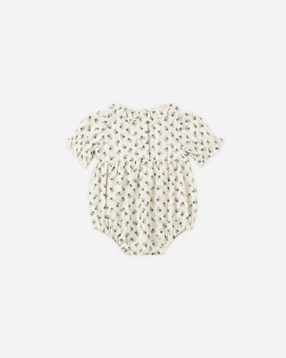 Back view of a natural cream floral print bubble romper laid flat, showing the button closure down the back, ruffle collar, and puff sleeves with ruffled cuffs.