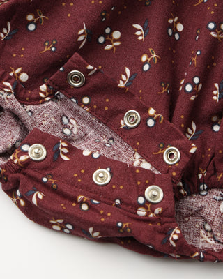 Close-up of a burgundy fabric with floral patterns and buttons on a white background