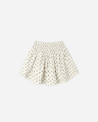 Ivory floral print mini skirt laid flat, featuring a smocked elastic waistband and a scalloped hem.