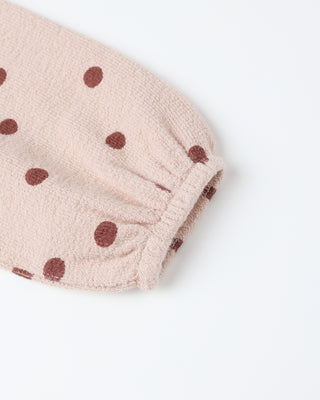 sleeve detail with brown polka dots on a white background
