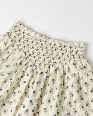 Close up of ivory floral print mini skirt laid flat, featuring a smocked elastic waistband.