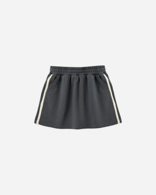 Midnight blue fleece mini skirt laid flat, featuring an elastic waistband, side pockets, and a cream side stripe running down each leg.