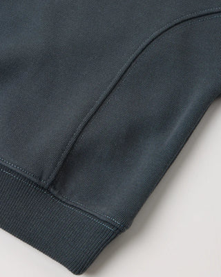 Close-up of a midnight blue sweatshirt hem showing curved seam detailing and ribbed cuff and waistband.